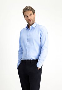 Lichtblauw overhemd met lange mouwen, knopen, een kraag, rechte snit, gladde stof en witte knopen, gecombineerd met een zwarte broek.