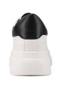 Sneaker bianca con un cappuccio sul tallone in pelle nera, texture liscia, colletto imbottito e una spessa suola in gomma bianca con branding in rilievo.