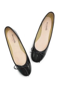 Ballerine in vernice nera con punta arrotondata, bordo elastico e un piccolo fiocco decorativo sul davanti. Soletta beige.