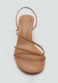 Tan strappy sandal with a flat sole. Features thin straps and a slight heel. Smooth texture with minimal stitching detail. Gold logo on the insole.