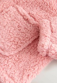 Rosa, flauschiger Stoff mit einer strukturierten Oberfläche und sichtbaren Fasern. Weicher und warmer Eindruck, mit einem zerknitterten Design. Ideal für gemütliche Kleidung.