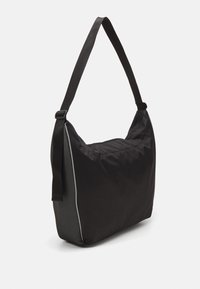 Černá kabelka přes rameno s měkkým, texturovaným tělem a síťovaným bočním panelem. Disponuje širokým, nastavitelným popruhem a minimalistickým designem.