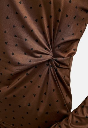 Braunes Oberteil aus glattem Stoff, mit einem verstreuten schwarzen Herzmuster und einem gerafften Detail auf einer Seite für zusätzliche Textur.