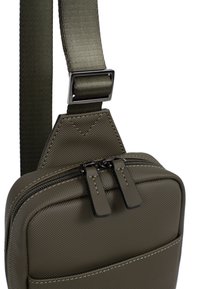 Borsa a tracolla in nylon verde oliva con superficie texture, dotata di due compartimenti con zip e una tracolla regolabile con hardware metallico.