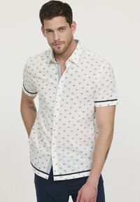 Korte mouwen button-up shirt in wit met marineblauwe stippen, contrasterende gestreepte binnenkraag en marineblauwe accenten bij de manchetten en zoom.