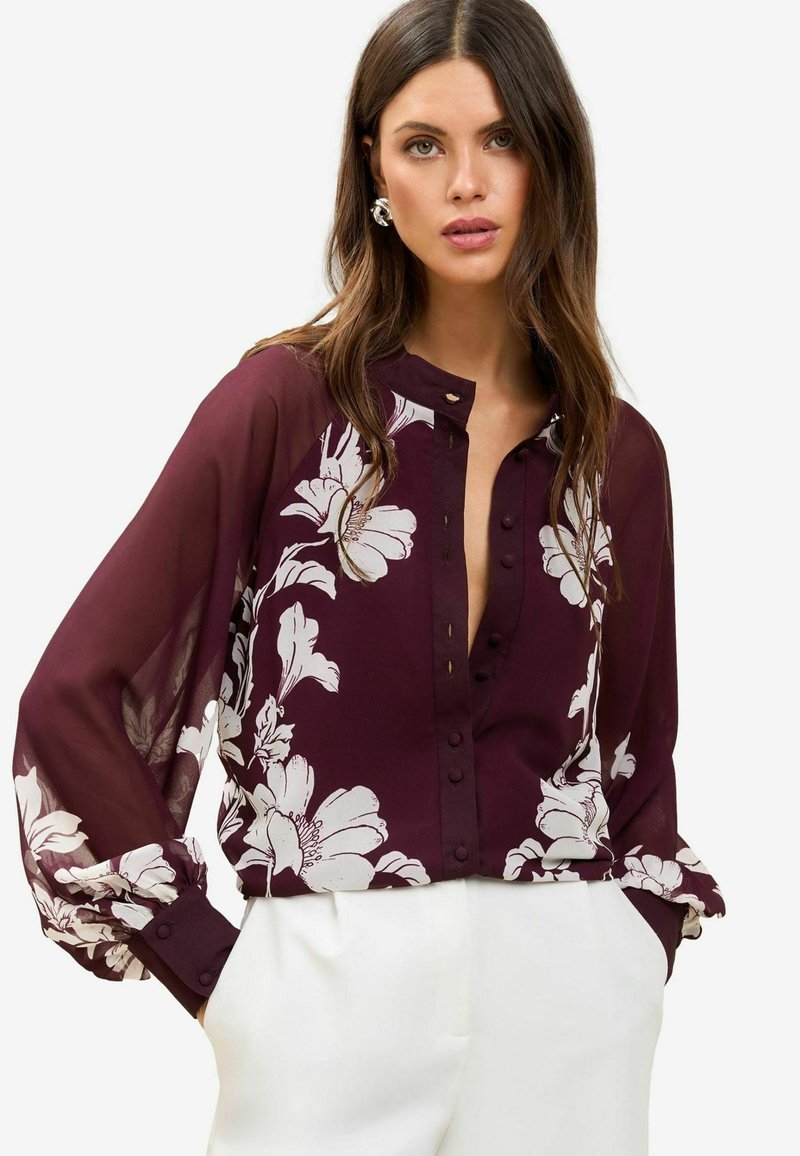 Burgundy blouse with white floral pattern, long sheer sleeves, button front closure, and a relaxed fit. Soft texture with a lightweight appearance.
