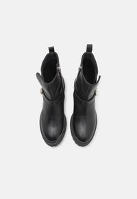 Botas de tobillo de cuero negro con un acabado suave, cremalleras laterales y una suela ligeramente rugged. Cuenta con una pestaña en la parte posterior para facilitar su uso.