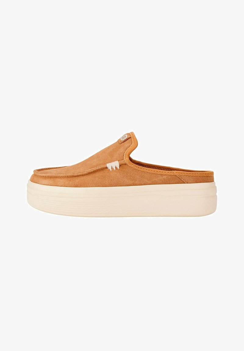 Slip-on shoe in tan suede with a smooth texture, featuring a white accent stitch and a thick cream sole for added height.