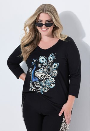 Maglietta nera a maniche lunghe con una grafica di pavone in blu e bianco, abbinata a pantaloni neri con un pannello laterale a stampa leopardata.