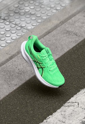 Groene sportieve schoen met een textiel bovenwerk, een lichte zool en zwarte accenten. Heeft een gevoerde kraag en vetersysteem.