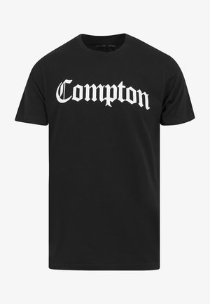 Schwarzes Baumwoll-T-Shirt mit dem Aufdruck "Compton" in großen weißen gotischen Buchstaben auf der Vorderseite. Standard Rundhalsausschnitt und kurze Ärmel.