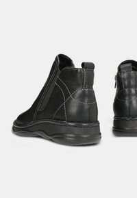 Stivaletti neri in pelle con pannelli elastici laterali, cuciture dettagliate, suola in gomma flessibile e accenti testurizzati. Adatti per un abbigliamento casual.