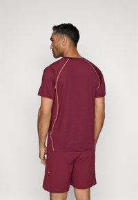 Μαρουανί αθλητικό μπλουζάκι με κοντό μανίκι και πορτοκαλί ραφές αντίθεσης. Συνδυασμένο με μαρουανί κοντό παντελόνι. Ιδανική υφή.