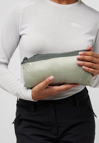 Pouch leggero verde con finitura opaca, dotato di una zip grigia nella parte superiore. Logo testurizzato e "STOWAWAY" stampato su un lato.