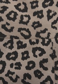 Tela con estampado de leopardo en tonos de beige y negro, que presenta patrones irregulares y una superficie ribeteada texturizada. Con acentos oscuros únicos por toda la tela.