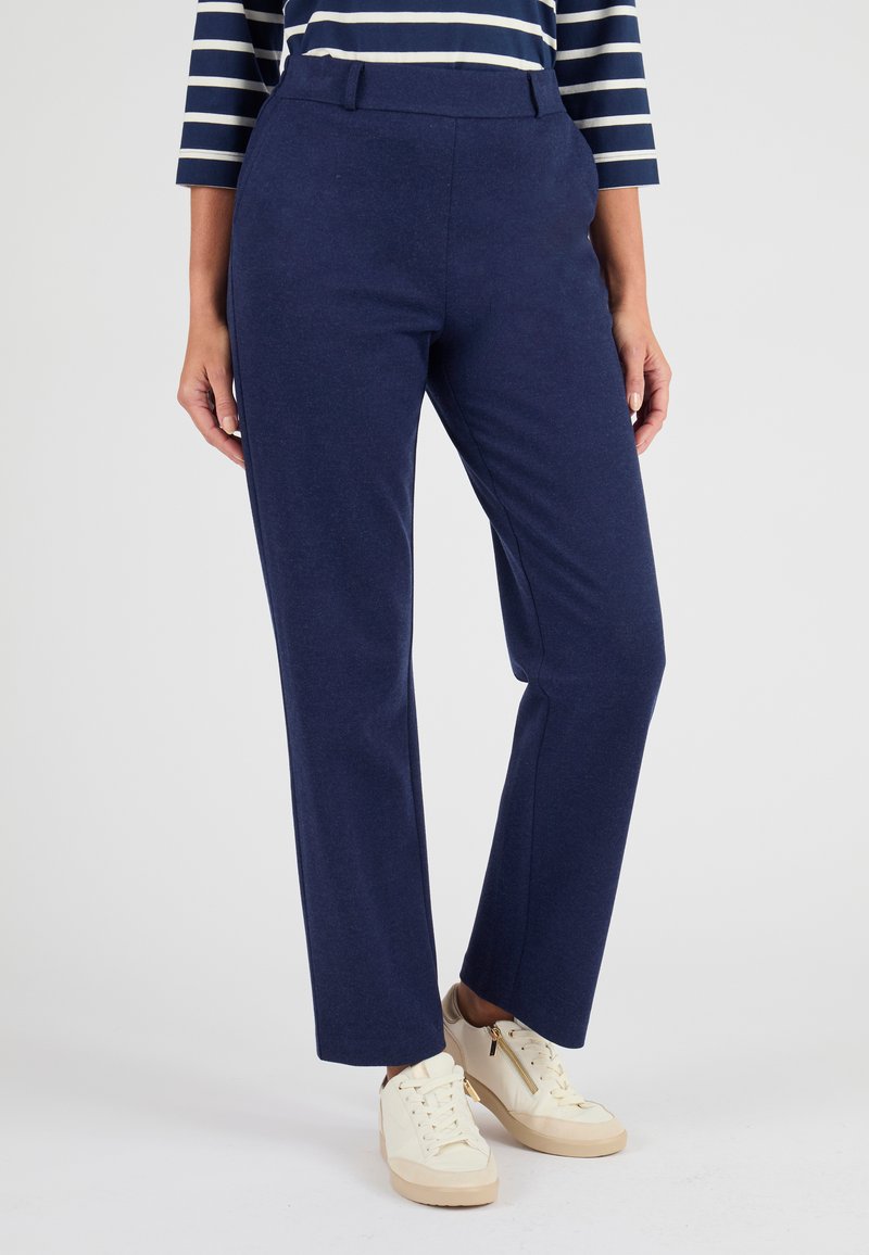 Pantaloni dritti blu navy realizzati in tessuto morbido, con vita e tasche laterali. Abbinati a sneaker di colore chiaro.