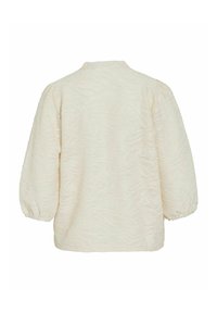 Light beige textured blouse with long puff sleeves, featuring a subtle wavy pattern and a simple round neckline.