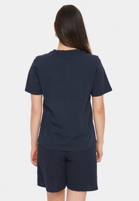 Mörkblå t-shirt med kort ärm, rund halsringning och mjukt tyg; ihop med strukturerade mörkblå shorts.