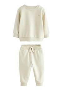 Ensemble de sweat-shirt et de joggers de couleur crème, fabriqué en tissu doux. Comprend des poignets côtelés, une taille élastique et un logo brodé minimaliste.