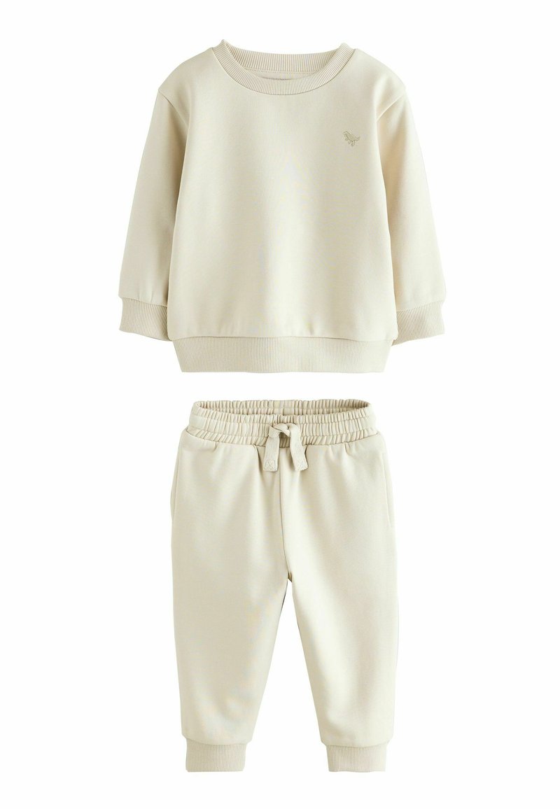 Ensemble de sweat-shirt et de joggers de couleur crème, fabriqué en tissu doux. Comprend des poignets côtelés, une taille élastique et un logo brodé minimaliste.