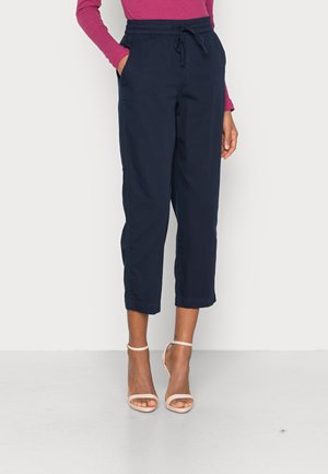 Pantalons cropped bleu marine en tissu tissé, dotés d'une taille élastique avec cordon de serrage et de poches latérales. Détail d'ourlet empilé.