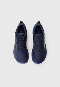 Une paire de chaussures de course bleu marine avec des lacets noirs et des accents bleus, vue de dessus sur un fond gris clair.