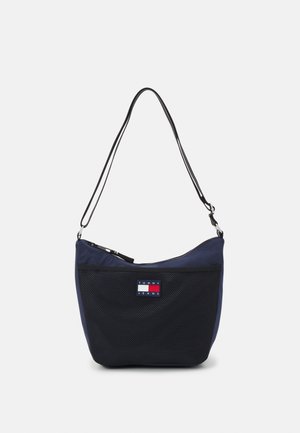 Bolso de hombro de nailon azul marino con frente de malla, cierre de cremallera y correa ajustable. Presenta un parche con el logo de Tommy Jeans en rojo, blanco y azul.