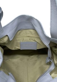 Světle modrá kožená kabelka s béžovou látkovou vnitřní stranou, zipovou kapsou a prošitým logem značky.