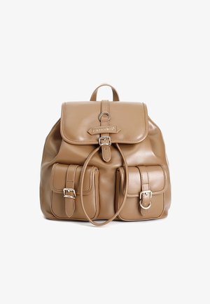 Mochila de imitación cuero color marrón claro con cierre de solapa, correas ajustables y dos bolsillos frontales. Presenta herrajes en tono plata y detalles de costura.