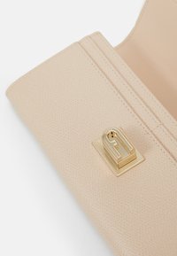 Portafoglio in pelle beige texturizzata con una chiusura liscia color oro e cuciture sottili; l'interno presenta più scomparti per carte e spazio per denaro contante.