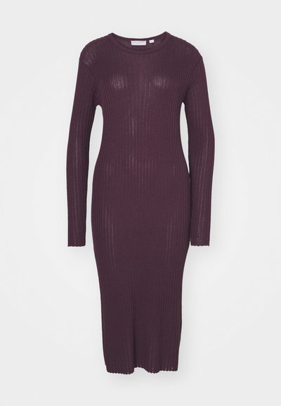 Hosszú ujjú bordázott ruha sötétlila színben. Élénk, testhezálló fazonja van, és kerek nyakkivágása díszes szegéllyel rendelkezik az ujjak végén.