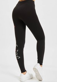 Sorte leggings med en jevn tekstur, med grå og røde detaljer. Designet inkluderer trykt tekst på siden og en høy midje.