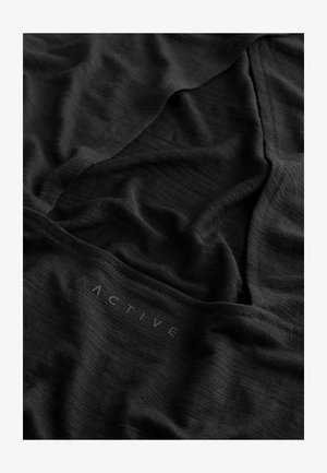 Čierna tkanina s textúrovaným povrchom, s jemnými záhybmi. Slovo "ACTIVE" je vytlačené moderným písmom blízko spodného okraja.