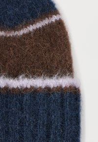 Helesinine, pruun ja heleroosa kootud müts. Omab tekstuurset, karvast materjali vahelduvate horisontaalsete triipudega ning soonilise alaäärega.