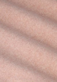 Tissu en coton de couleur rose doux avec une texture lisse et un motif de tricot fin et uniforme. Des variations subtiles de teinte sont visibles.