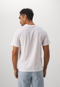 Hvid kortærmet T-shirt med rund hals, lavet af bomuld, der har en glat tekstur og en afslappet pasform, vist fra ryggen.