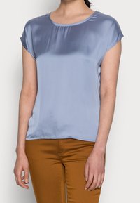 Blusa azzurra chiara a maniche corte in tessuto morbido con scollatura rotonda e vestibilità rilassata. Adatta per un abbigliamento casual.