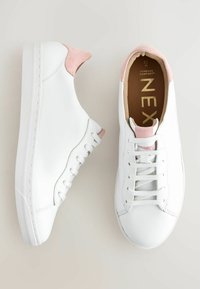 Baskets basses blanches avec des accents en daim rose sur le talon et la languette, des lacets blancs et des semelles intérieures marron rembourrées portant l'inscription "Forever Comfort ZEX".