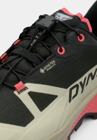 Μαύρο και κρεμ επαγγελματικό παπούτσι με ροζ λεπτομέρειες, με υφή στο άνω μέρος και ετικέτα GORE-TEX. Περιλαμβάνει σύστημα ασφαλούς δέσιμο και ανθεκτική σόλα.