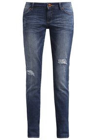 Jean skinny en denim bleu avec des déchirures usées sur le haut des cuisses et une fermeture à bouton à la taille.