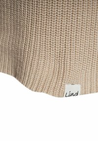 Beige gestrickte Mütze mit gerippter Textur. Verfügt über ein kleines weißes Etikett mit "Lind" in schwarzer Schrift am Rand.