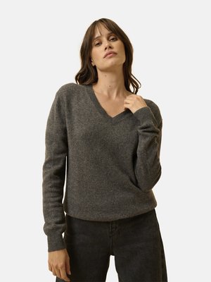 Maglione grigio in misto lana con scollo a V, maniche lunghe, polsini a coste e vestibilità rilassata, indossato sopra jeans scuri. Tessuto morbido, design minimal.