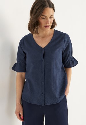 Navy blue button-up blouse with a v-neck, short puff sleeves, and textured fabric. Features a subtle pattern and a relaxed fit.