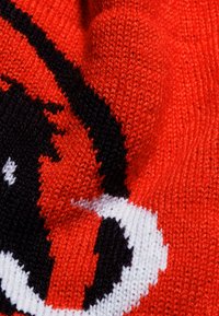 Sciarpa lavorata a maglia di un rosso vibrante con un motivo in bianco e nero. Presenta una superficie texturizzata e una trama più spessa, che mette in risalto il design intricato.