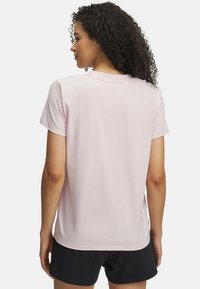 Camiseta de algodón color rosa claro con cuello redondo y mangas cortas, vista desde la parte de atrás. La tela parece suave y lisa.