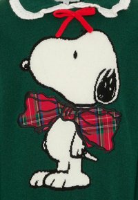 Maglione verde con Snoopy di profilo, con un design bianco, contorni neri e un papillon a quadretti rossi con accenti verdi.