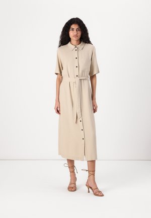 Abito button-up in misto lino beige con maniche corte, cintura con nastro e tasca frontale, abbinato a sandali con tacco alto beige con lacci.