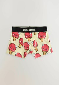 Boxers pour enfants avec un fond jaune, imprimés de raquettes de tennis de table rouges souriantes, et une ceinture noire portant l'inscription "TABLE TENNIS".