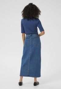 Jeans-maxikjol med hög midja, med två bakfickor och rak passform. Bärs med en figurnära blå topp och svarta skor.