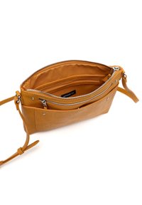 Bolso de cuero marrón con cierre de cremallera, múltiples compartimentos y una correa delgada ajustable. Textura suave y acentos de hardware mínimos.